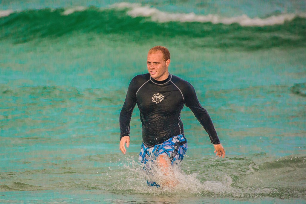 Image shows Nicholas emerging from the ocean waves.