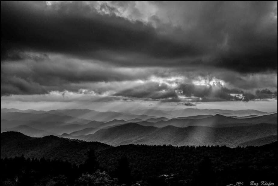 Light rays pierce clouds over the countryside.